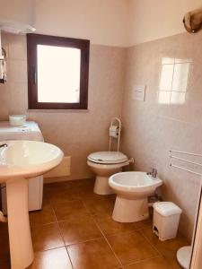 Un baño con lavabo, inodoro y ventana. en Siniscola Casa vacanze Olmo, en Siniscola