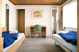 1 Schlafzimmer mit 2 Betten und einem Schreibtisch mit einem Stuhl in der Unterkunft B&B La Tgamona in Savognin
