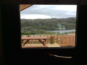 a window with a bench looking out at a river at Achmelvich View self catering in Lochinver