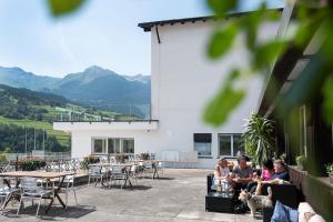 un groupe de personnes assises sur une terrasse avec des tables et des chaises dans l'établissement B&B La Tgamona, à Savognin