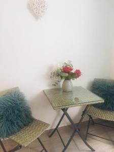 einen Tisch mit einer Vase aus Blumen und zwei Stühlen in der Unterkunft Guesthouse Dubrovnik in Dubrovnik