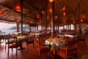 um restaurante com mesas e cadeiras e vista para o oceano em Bogmallo Beach Resort em Bogmalo