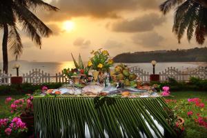 a table with food and flowers on it with the ocean at Bogmallo Beach Resort in Bogmalo