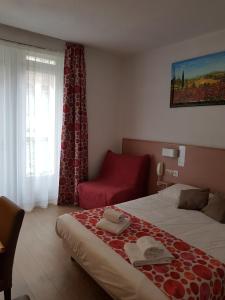 ルルドにあるHôtel de Parisのベッドと赤い椅子が備わるホテルルームです。