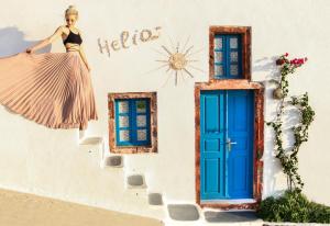 a woman standing in front of a building with a blue door at Santorini Paradise Cave Houses in Oia