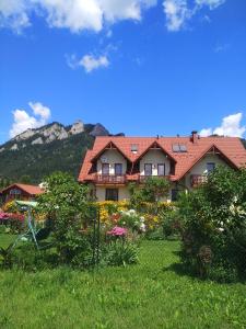 a large house with a garden and mountains in the background at Pokoje z aneksami kuchennymi u Wiktorii in Sromowce Niżne