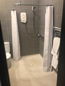 La salle de bains est pourvue d'une douche, de toilettes et d'un rideau de douche. dans l'établissement Aaron Glen Guest House, à Loanhead