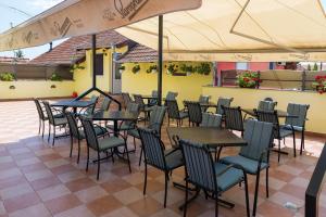 a row of tables and chairs under an umbrella on a patio at Rooms Gat in Subotica