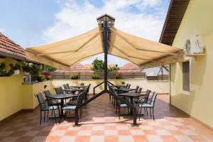 un patio avec des tables et des chaises sous un grand parasol dans l'établissement Rooms Gat, à Subotica