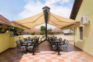 a patio with tables and chairs under a large umbrella at Rooms Gat in Subotica