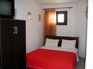 a bedroom with a bed with a red blanket at Golden Beach Inn in Chrysi Ammoudia