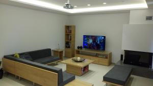 a living room with a couch and a flat screen tv at Heraklion Airport Family Lux Apartment in Heraklio