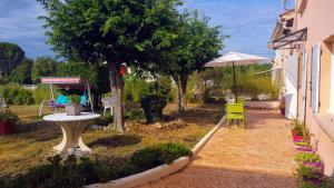 a patio with a table and a yellow chair and an umbrella at La Bedosse in Alès +5 photos