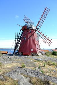 un gran molino de viento rojo sentado en la cima de una colina en Kvarnstugan en Mollösund