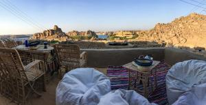 a patio with tables and chairs and a view of a mountain at Eco Nubia in Aswan