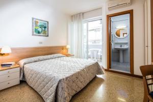 a bedroom with a bed and a bathroom with a sink at Hotel Meublè Zenith in Lignano Sabbiadoro