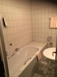 a white bathroom with a tub and a sink at Hotel & Restaurant Dortmunder Eck in Horn-Bad Meinberg