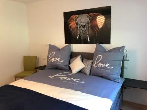 a bed with blue pillows and a picture of an elephant at Apartment Green Elephant in Tettnang