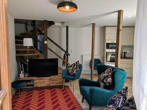 a living room with two blue chairs and a television at Gîte Rue des Fleurs Puycelsi in Puycelci