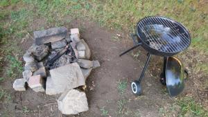 a grill and a pile of rubble next to a fire at Gyümölcsöskert Szálláshely in Debrecen