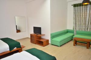 a room with a bed and a couch and a television at Yensfield Blackpool in Nuwara Eliya