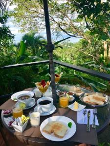 einen Tisch mit einem Frühstück mit Toast, Kaffee und Saft in der Unterkunft Casa del Toucan in Dominical