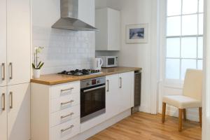 uma cozinha com armários brancos e um fogão com forno em Central Brighton Town House by MyHolidayLet em Brighton & Hove mais 15 fotografias