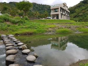 a house on a hill next to a body of water at Antong Creekside Hot Spring in Yuli