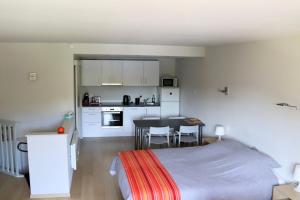 a room with a bed and a kitchen with a table at Le Pré-Chet in Profondeville