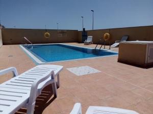 a swimming pool on top of a building with white benches at Chalet Ocean in El Médano