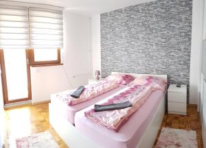 een slaapkamer met een roze bed en een bakstenen muur bij Apartment Emina in Travnik