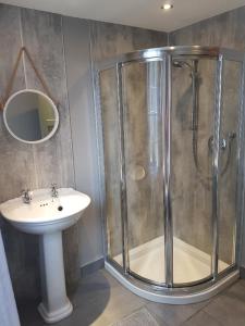 uma casa de banho com um chuveiro e um lavatório. em The Castle Apartment em Strangford