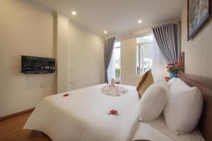 um quarto com uma cama branca e almofadas brancas em Spoon Hotel em Hanói