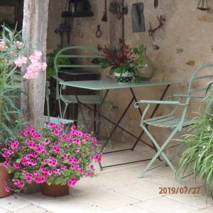 un patio con mesa, sillas y flores en La Pierre qui Parle en Luynes