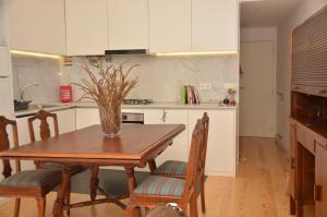 eine Küche mit einem Holztisch mit Stühlen und einer Vase in der Unterkunft Jenny and Carmie TOWN HOUSE in Viana do Castelo