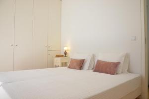 a white bedroom with a white bed with pillows at Jenny and Carmie TOWN HOUSE in Viana do Castelo