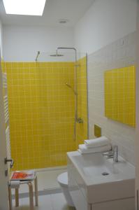 La salle de bains est pourvue d'un lavabo, d'une douche et de carrelage jaune. dans l'établissement Jenny and Carmie TOWN HOUSE, à Viana do Castelo