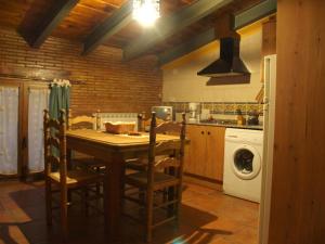 cocina con mesa y lavadora en Apartamentos Rurales Casa del Tio Juan, en Olocau del Rey