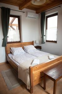 um quarto com uma grande cama de madeira e 2 janelas em Levendula Apartman em Hegykő