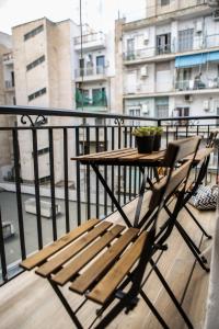eine Holzbank auf einem Balkon mit einem Tisch in der Unterkunft LM Luxury Central Loft in Larisa