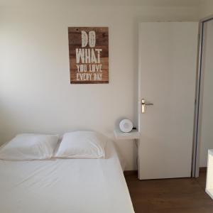 a bedroom with a white bed and a sign on the wall at Ty Breizh in Erdeven