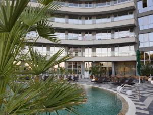 an apartment building with a swimming pool and palm trees at Allure Beach Resort Aparthotel in Primorsko