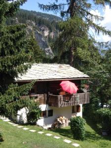una casa con una sombrilla roja en el balcón en Alter Lärch en Blatten bei Naters