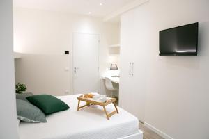 um quarto branco com uma cama e uma televisão na parede em Ml rooms em Lovere