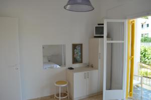 une cuisine avec des placards blancs, une table et un tabouret dans l'établissement Yellow House, à Kavos