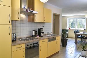 una cucina con armadi gialli e tavolo di Ferienwohnung Bella a Fuhlendorf