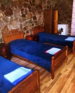 2 Betten mit blauer Bettwäsche in einem Zimmer mit einer Steinmauer in der Unterkunft SADA Guesthouse in Wardsia