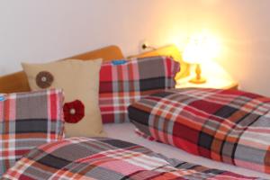 a bedroom with two beds with plaid pillows and a lamp at Haus Friedeck in Ramsau am Dachstein