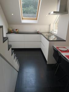 eine weiße Küche mit Spüle und Fenster in der Unterkunft Luxueus duplex appartement aan zee in Koksijde