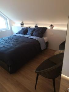 ein Schlafzimmer mit einem großen Bett und einem Stuhl in der Unterkunft Luxueus duplex appartement aan zee in Koksijde